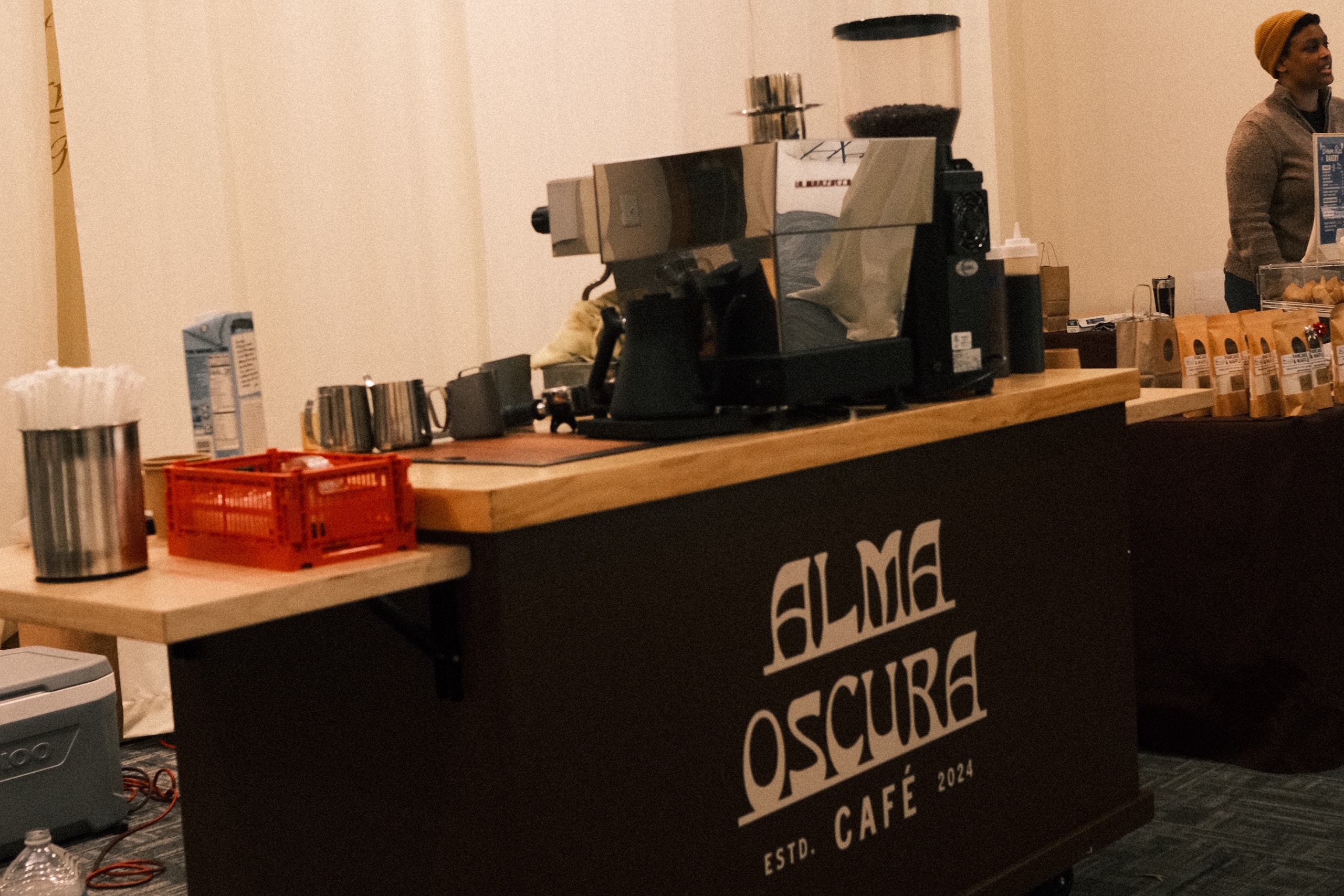 Alma Oscura Café — the branded mobile coffee counter in service: espresso machine, grinder and the Alma Oscura Café wordmark on the bar front