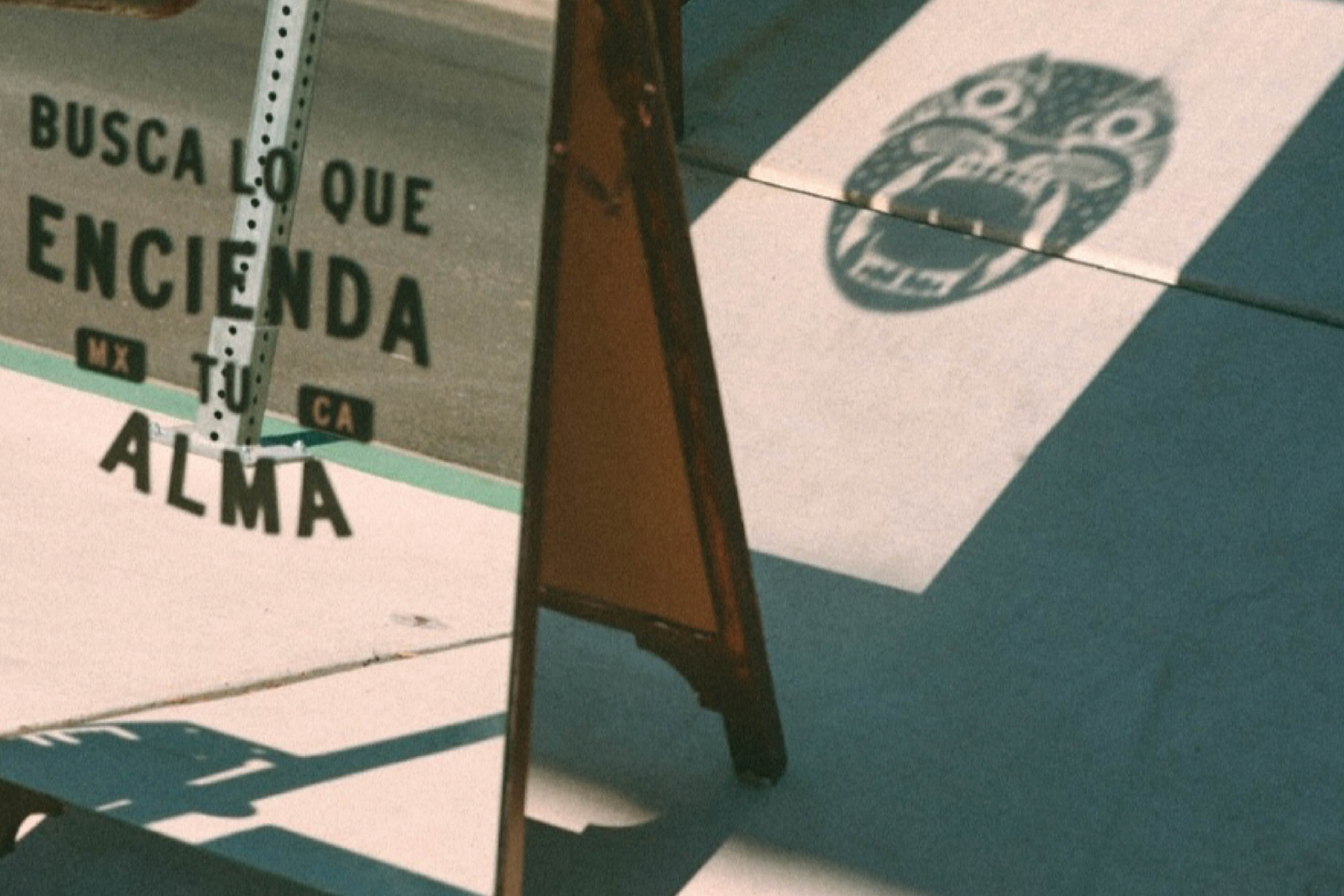 Alma Oscura — the A-frame sidewalk sign reading Busca Lo Que Encienda Tu Alma, with the jaguar face on the reverse panel, in sunlight