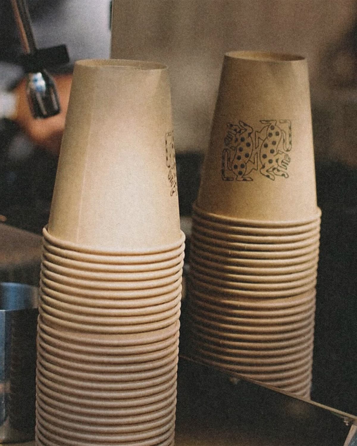 Alma Oscura — stacked branded paper cups with jaguar illustration