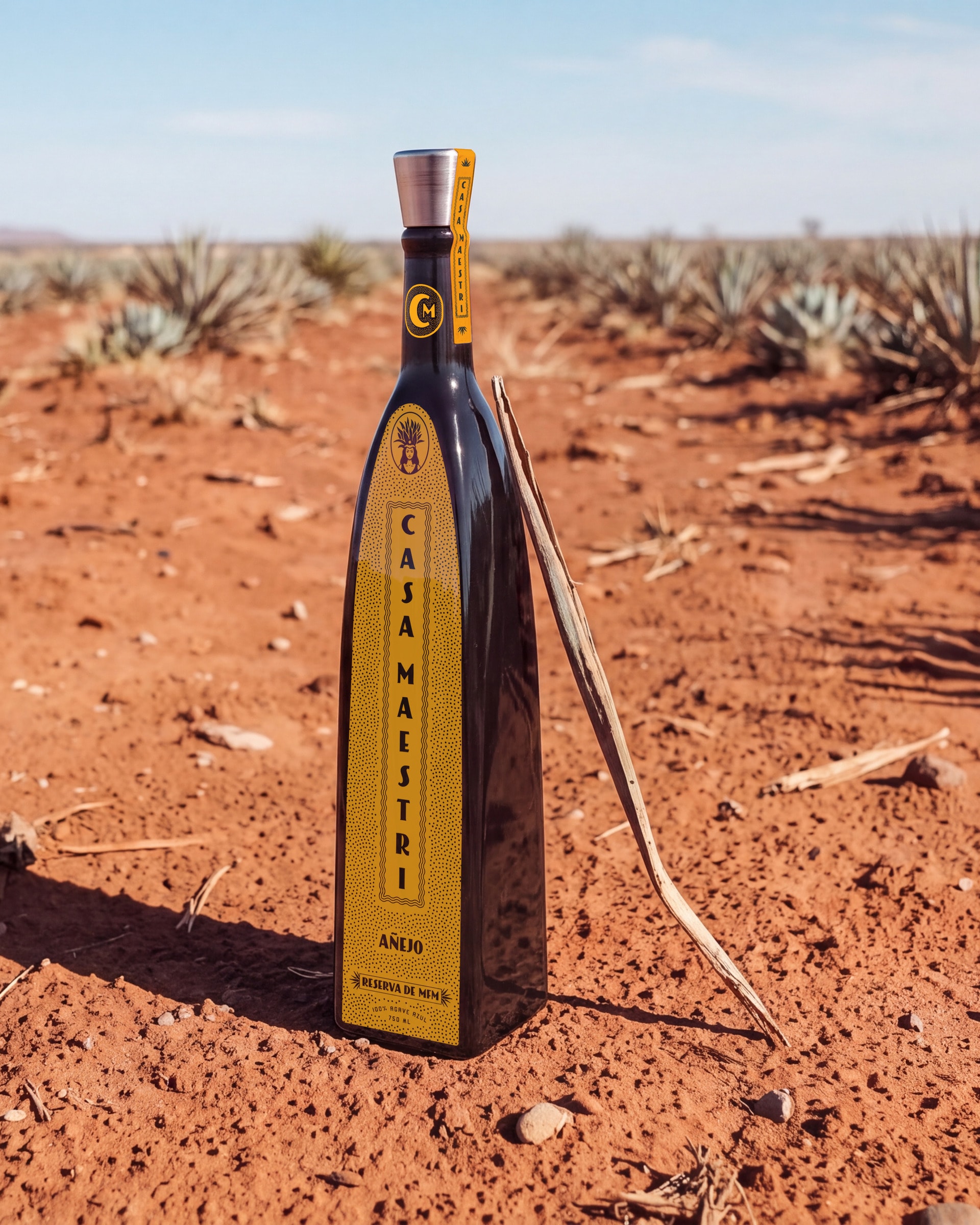Casa Maestri — Añejo bottle standing in the red soil of an agave field
